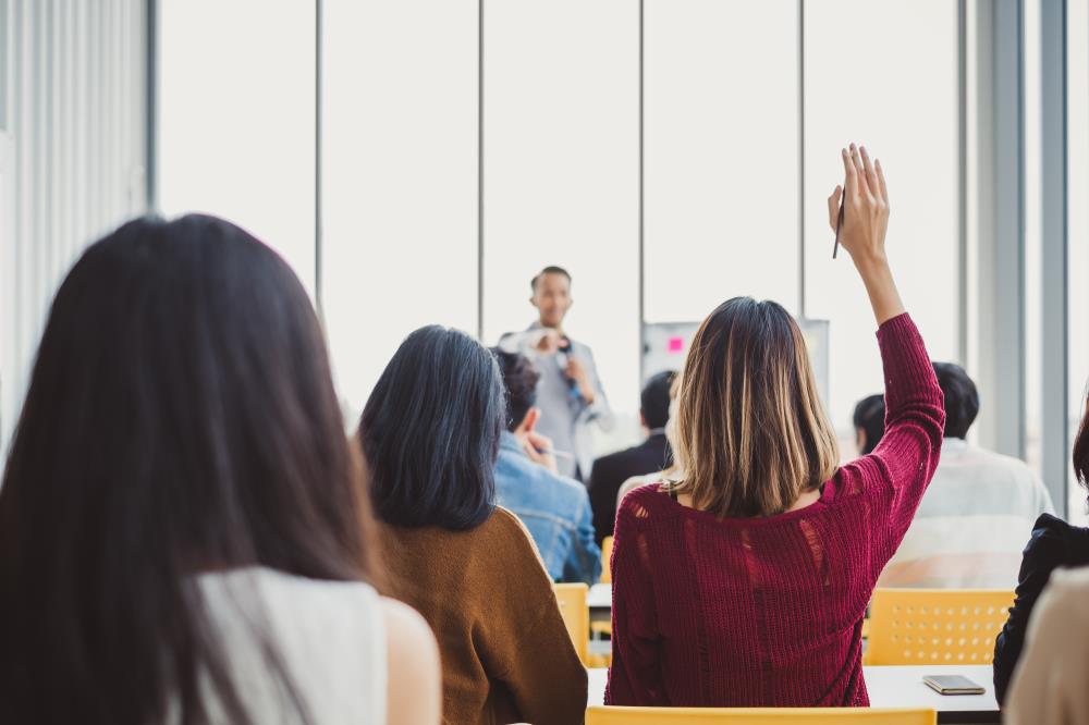 Woman raising hand to ask the presenter a question