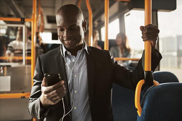 Smiling man listening to something on his phone on the bus