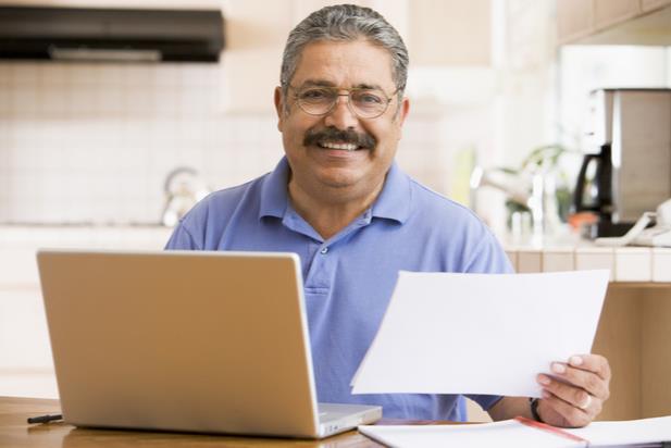 man holding up paper by computer