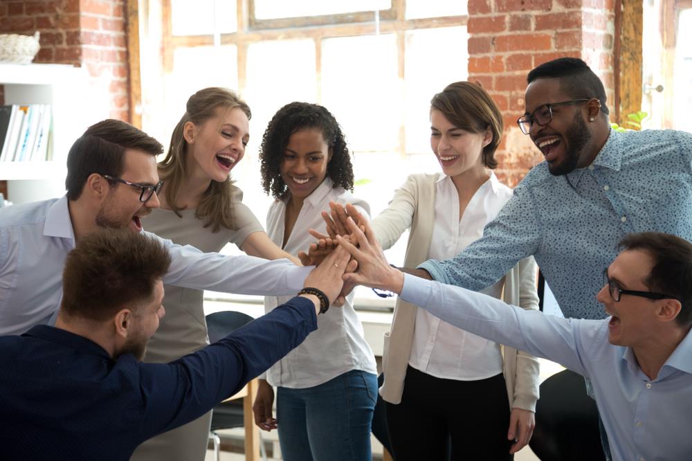 team putting their hands together to celebrate a big success in their office