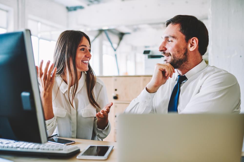 manager actively listening to his team member's ideas at her desk