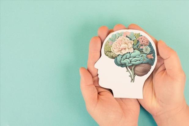 hands holding an illustration of a brain with flowers in it