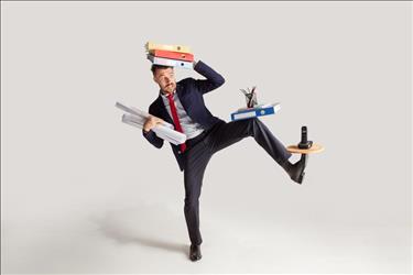 professional with multiple jobs trying to balance various items on his head, arms, knee, and foot