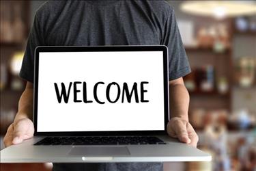 Man holding laptop that says "Welcome" on the screen