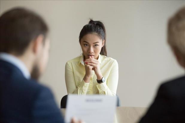 Candidate looking nervous in interview as hiring managers review her resume