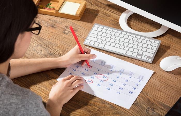 Woman circles new date on calendar in red pen