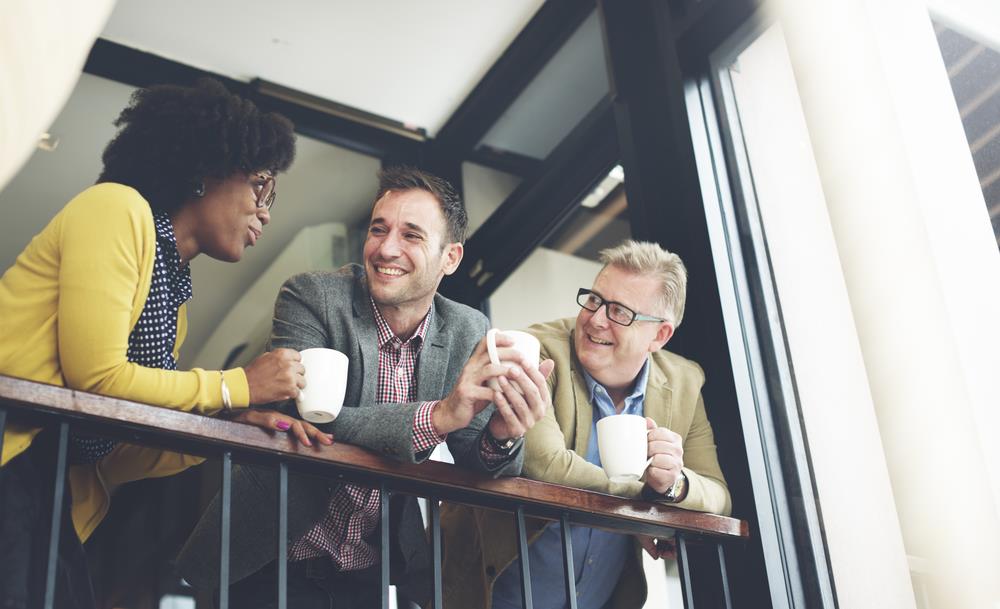 3 professionals having a pleasant conversation while drinking coffee