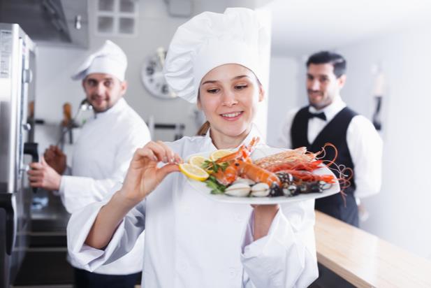 chef holding a dish with seafood