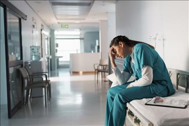 worried healthcare worker with her head in her hands
