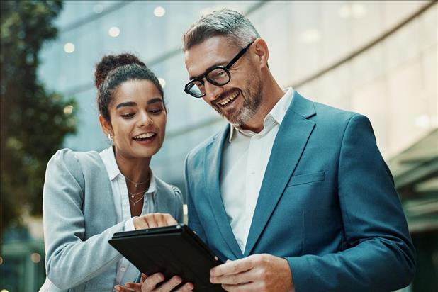 two smiling coworkers looking at a tablet together