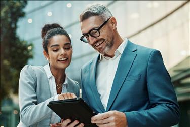 two smiling coworkers looking at a tablet together