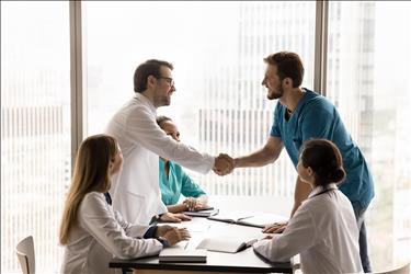 two medical employees shaking hands during a meeting