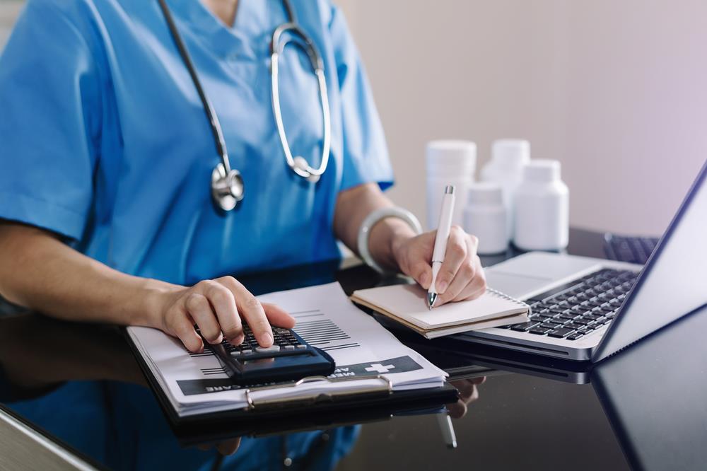 medical professional looking at her laptop and doing calculations