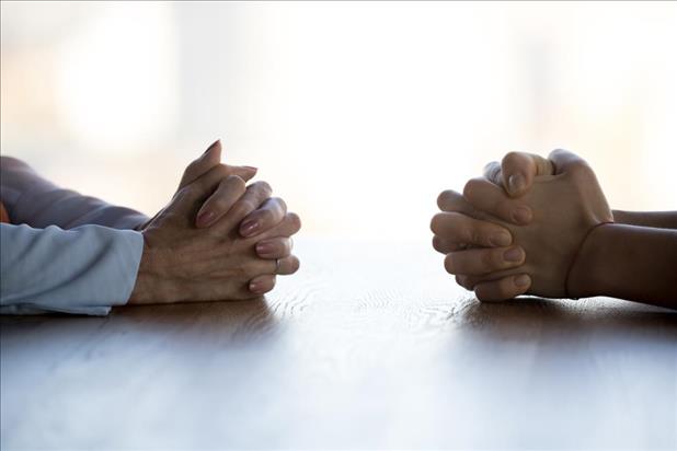 two sets of clasped hands on a table