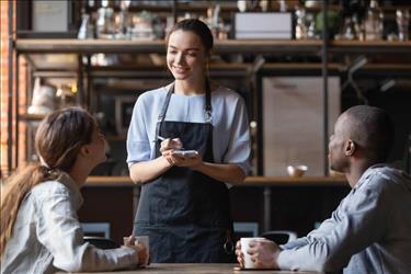 waitstaff taking orders from two customers at a cafe