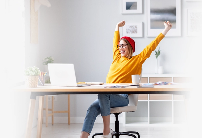 Woman happy at desk looking at laptop