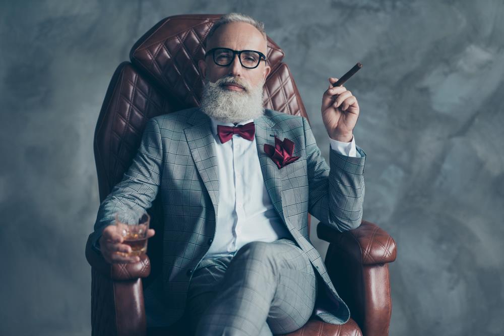 formally dressed man in a tuxedo sitting on a fancy chair