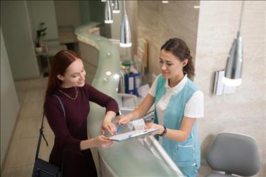 Dental office manager helping patient with paperwork