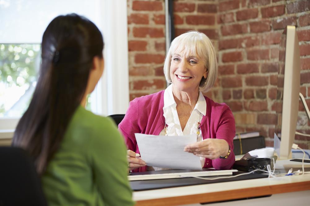 interviewer smiling at a candidate while interviewing them in her office