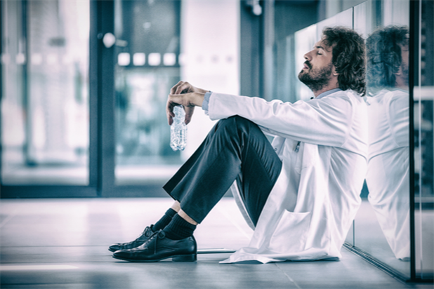 Doctor suffering from optometry burnout and leaning against a wall