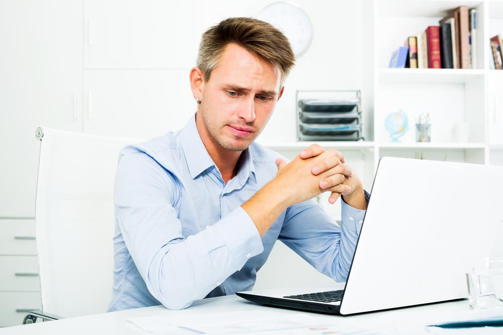 job seeker worried about his recent job loss while searching for jobs on his laptop