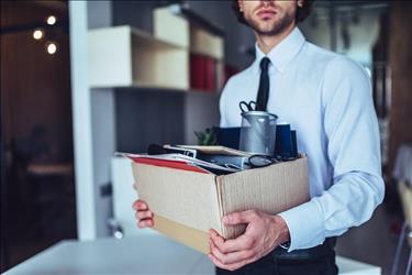 recently let go employee walking out of his office with his things in a box