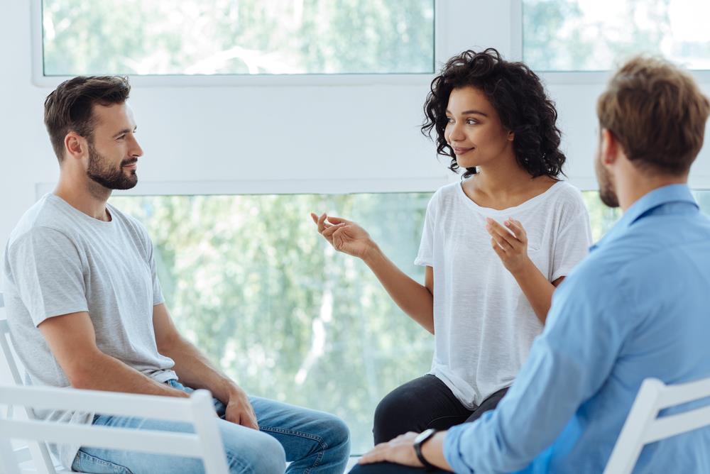 female mental health counselor holding a group session with two male clients