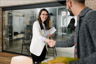 recruiter shaking hands with a new hire in her modern office