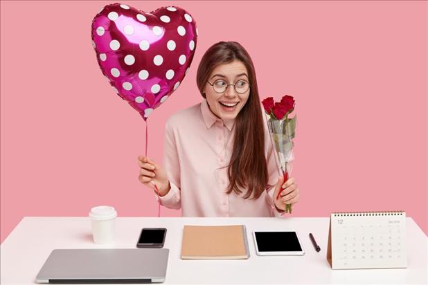 Woman at office holding roses and heart-shaped balloon