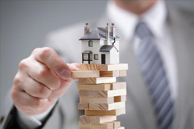 Man playing Jenga with house teetering on top