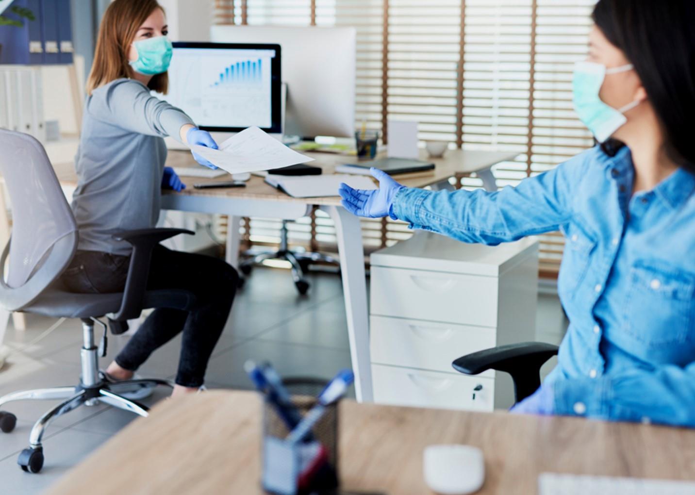 employees with PPE passing paper