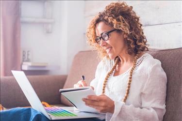 Woman taking notes, working on laptop