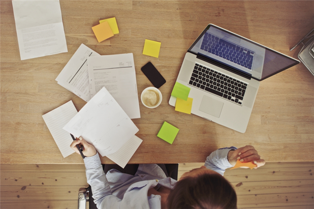 Top view of woman in front of laptop surrounded by papers while working on her resume