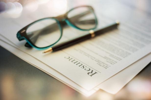 resume on a desk with pen and glasses on top of it