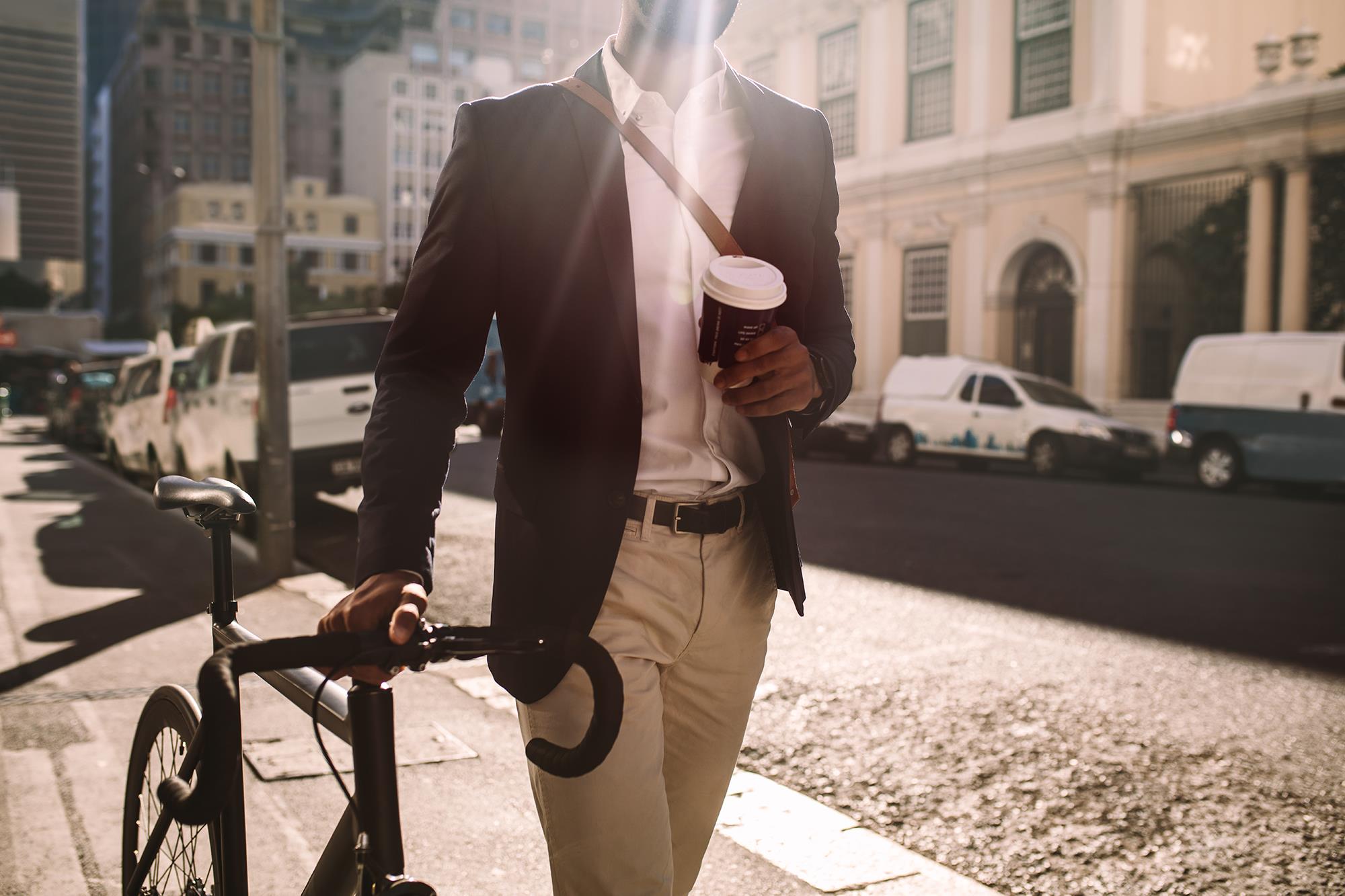 Man walking bike and drinking coffee