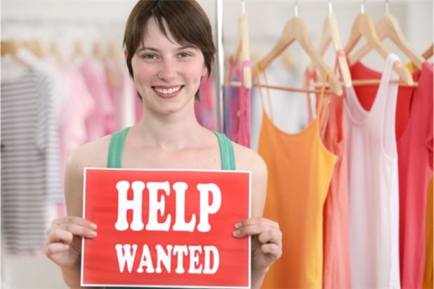 woman holding up a help wanted sign