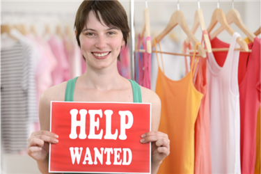 woman holding up a help wanted sign