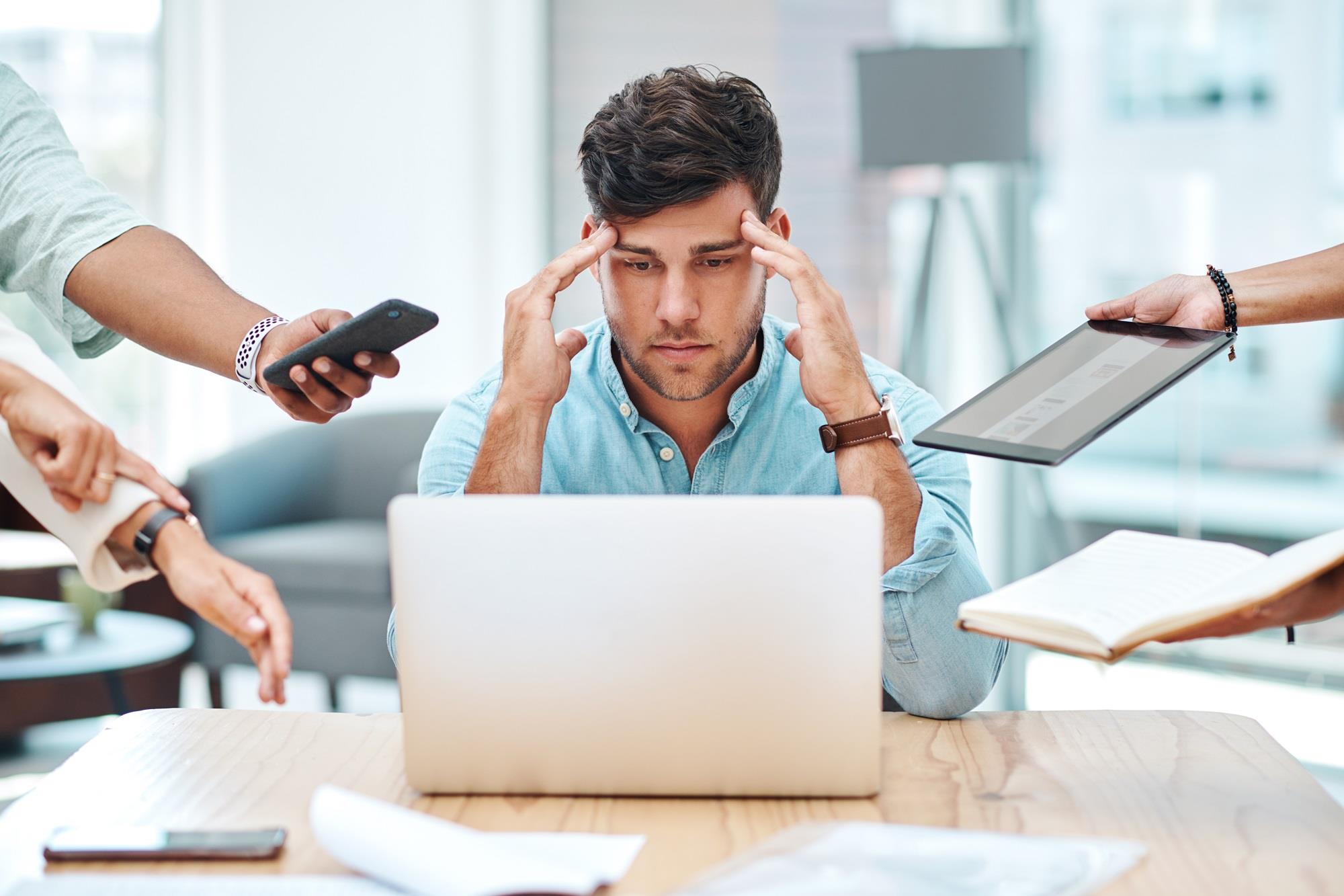 overworked employee with many people handing him things