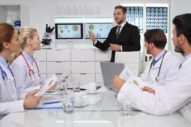 healthcare administrator giving a presentation to a team of doctors