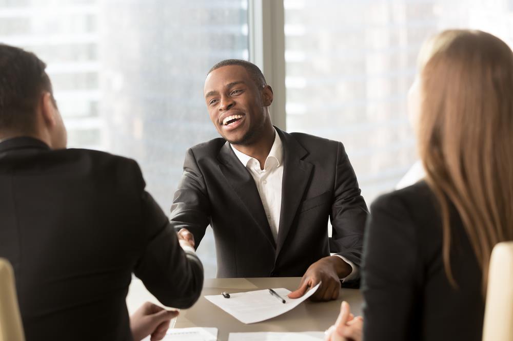 job seeker at a panel interview shaking one interviewer's hand