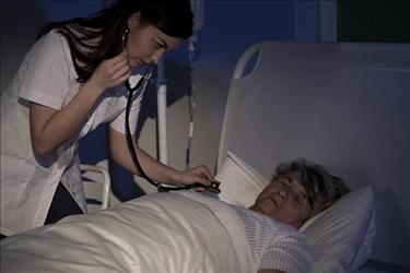 Nurse taking vitals of sleeping patient during her night shift