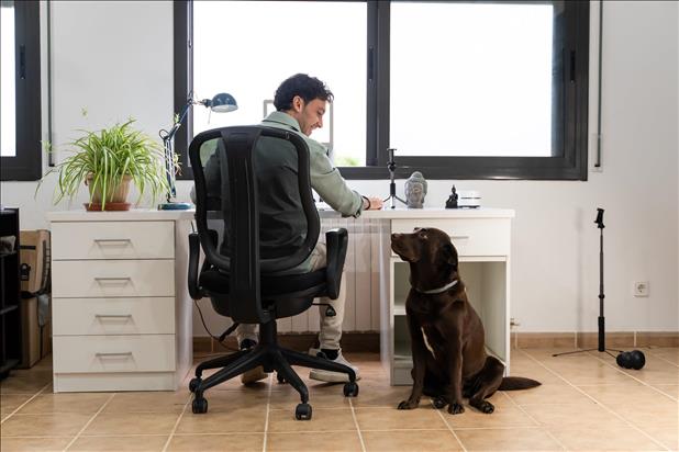 man smiling with his dog in his home office