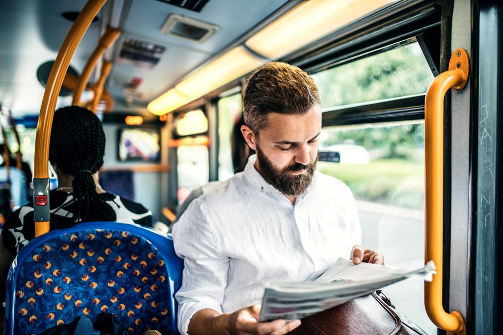 Man reading newspaper on the bus on his way to work