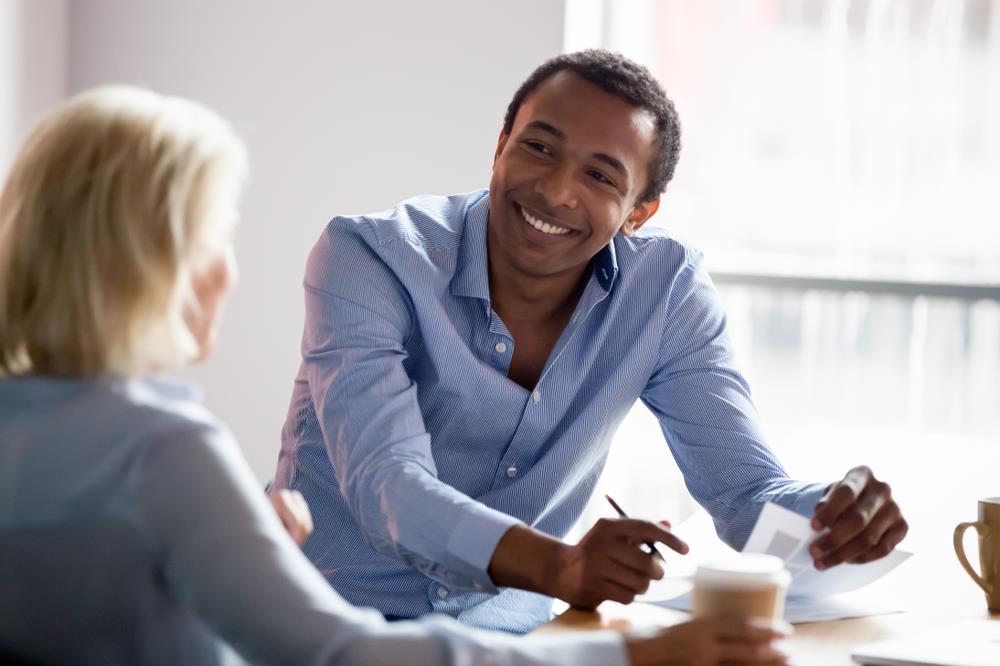 Happy employee talking to boss at work