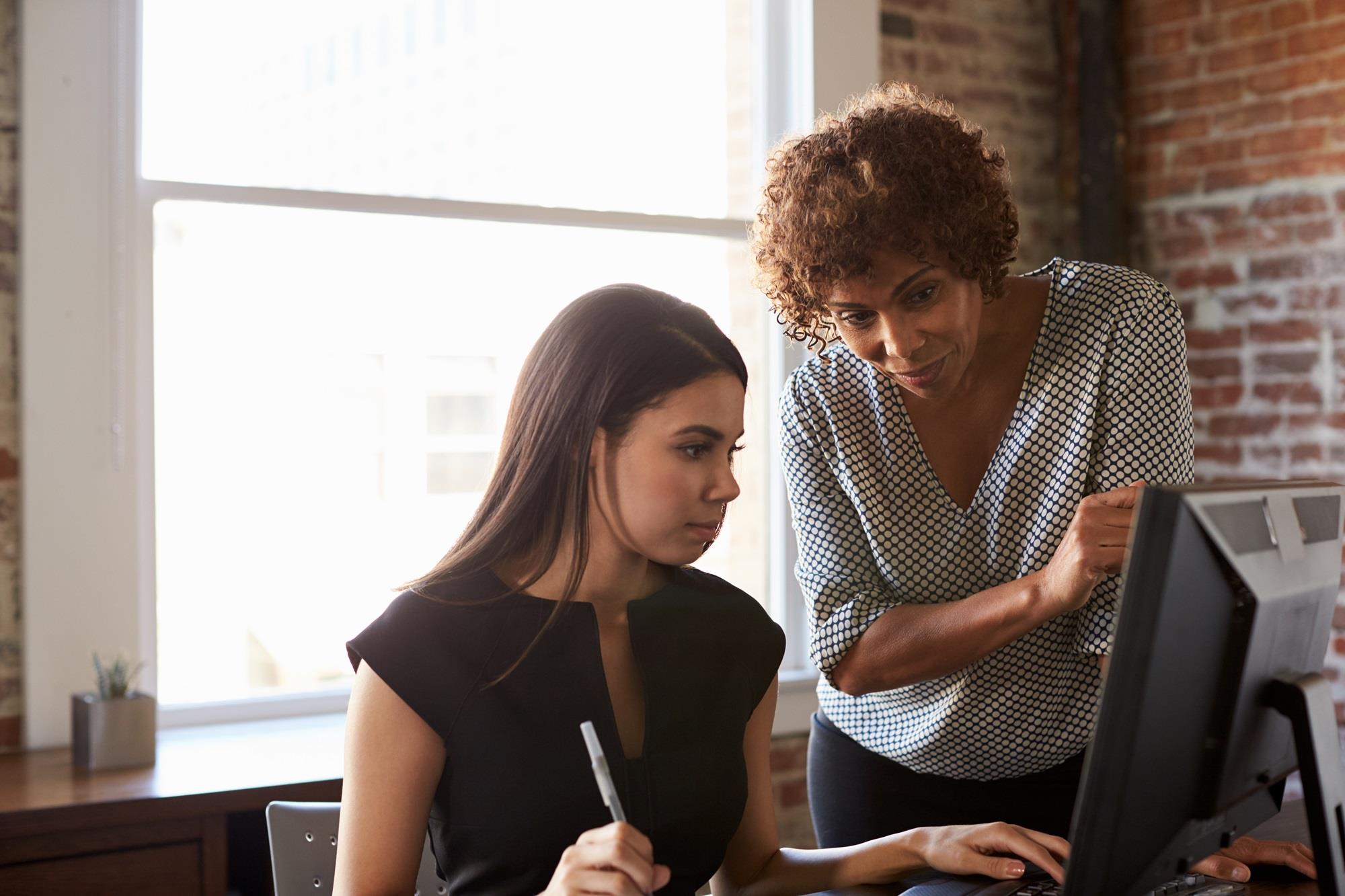 mentor helping her mentee at her desk