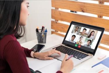 woman looking at a laptop with remote hiring team while working from home