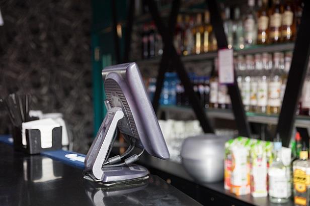 View of an empty restaurant with POS system sitting on bar