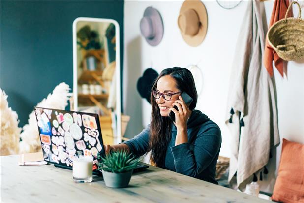 freelance employee on the phone while working on her laptop