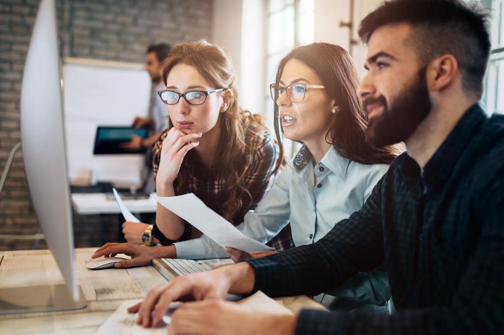 Employees working together and looking at a computer