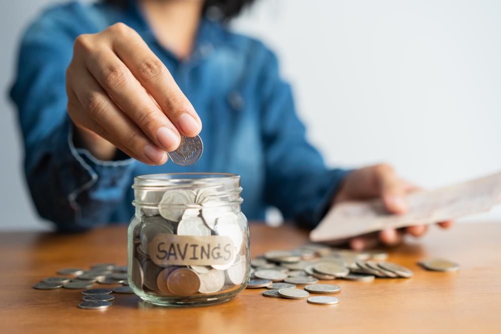 Woman putting money in savings jar